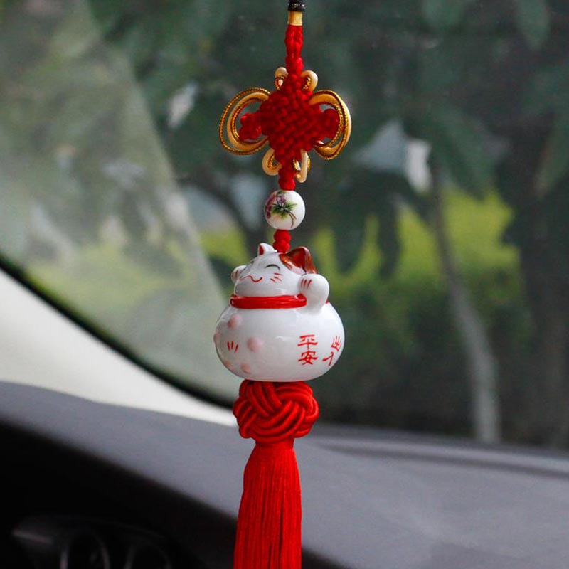 This japanese car charms is a white Japanese cat in ceramic material and kanji painting. The cat brings good luck and is a Japanese decorative object hanging from red threads.