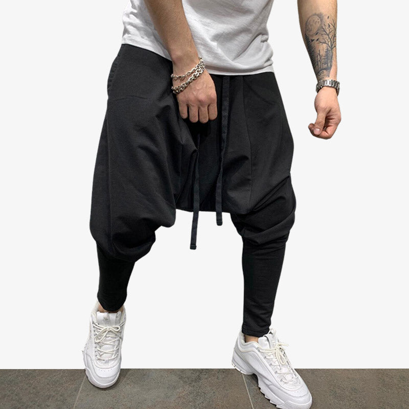 A man is standing wearing Japanese cargo pants streetwear. He is also wearing a white t-shirt and white sneakers.