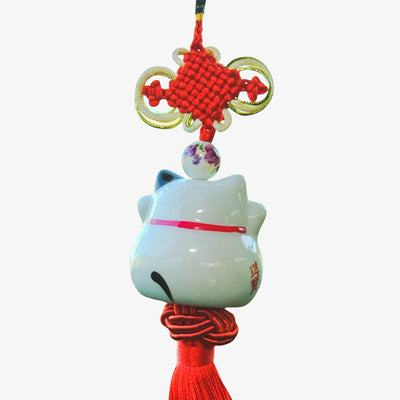this japanese cat charms hangs from a rear-view mirror. It is a Japanese decoration in the shape of a white cat.