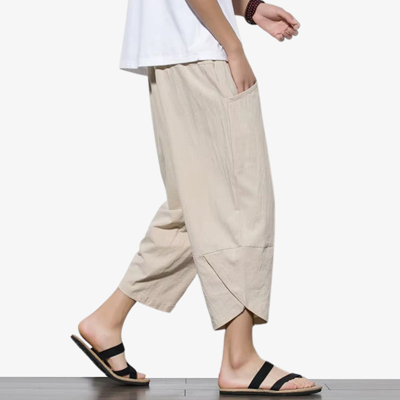A man is dressed with a beige minimalist japanese cropped pant with black sandals on feet