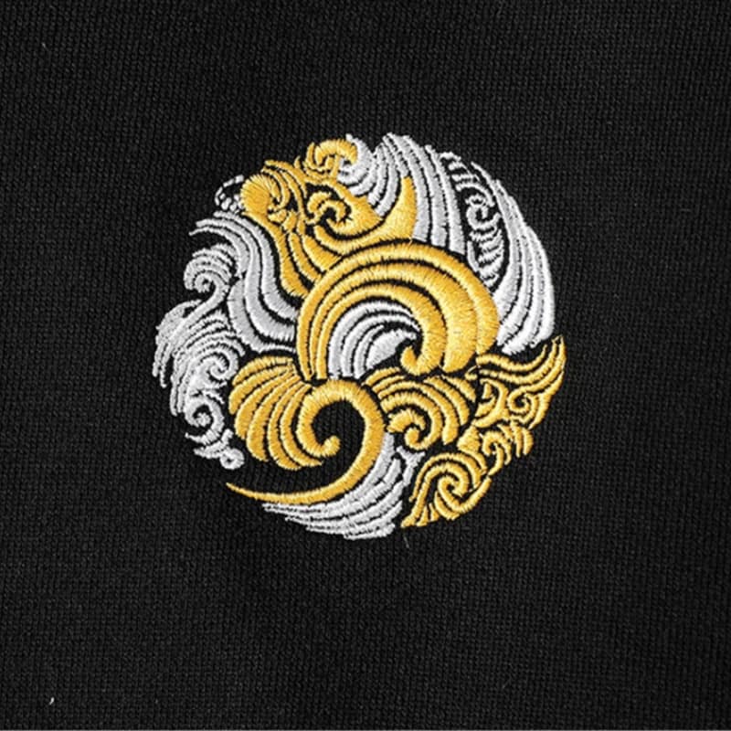 Japanese Embroidered design of two interlocking spiral patterns in gold and silver on a black background.