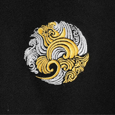 Japanese Embroidered design of two interlocking spiral patterns in gold and silver on a black background.