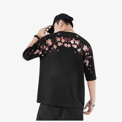 Person wearing a black floral shirt with pink flowers on a white background