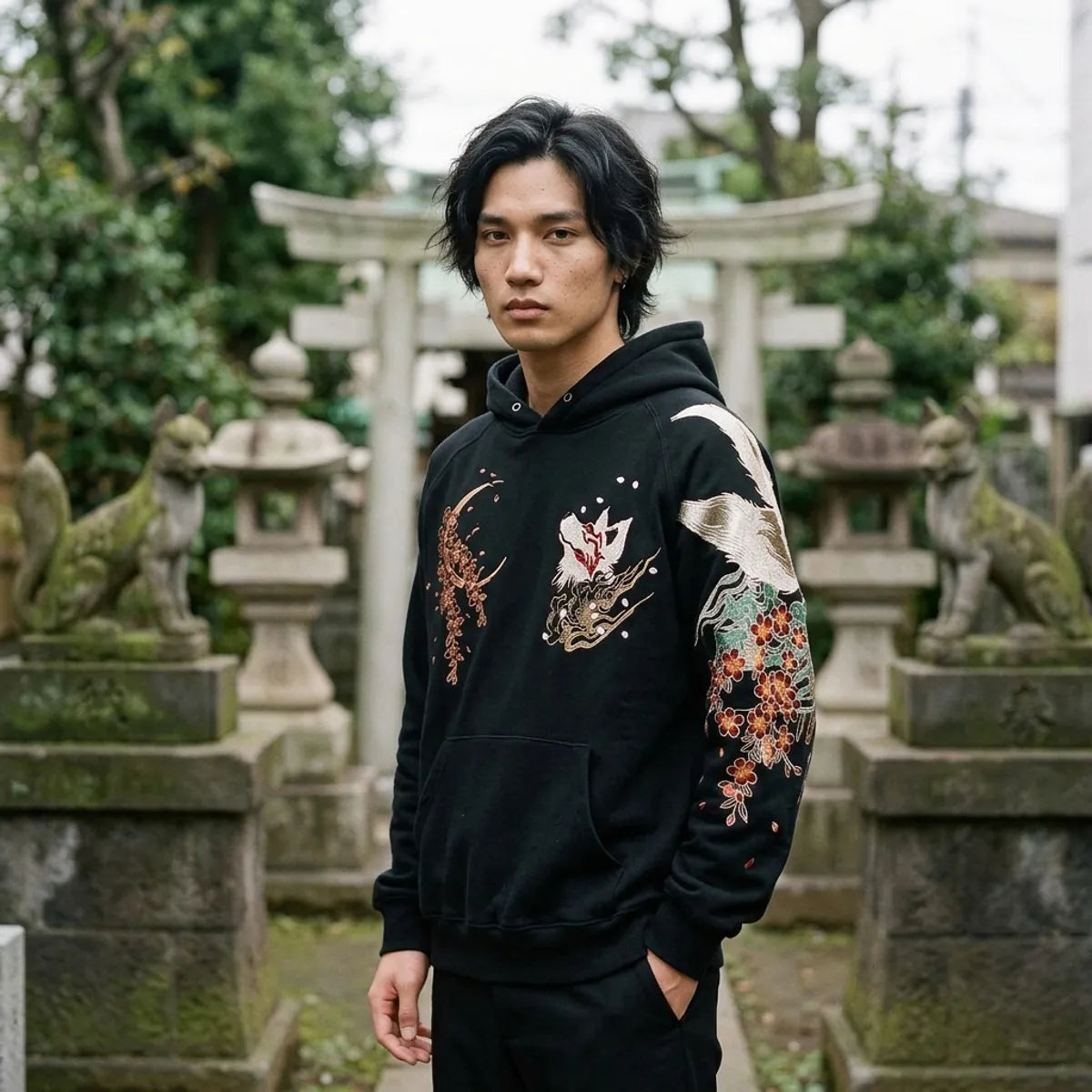 The Japanese fox hoodie worn at a small Inari shrine in Tokyo, stone fox statues beside him