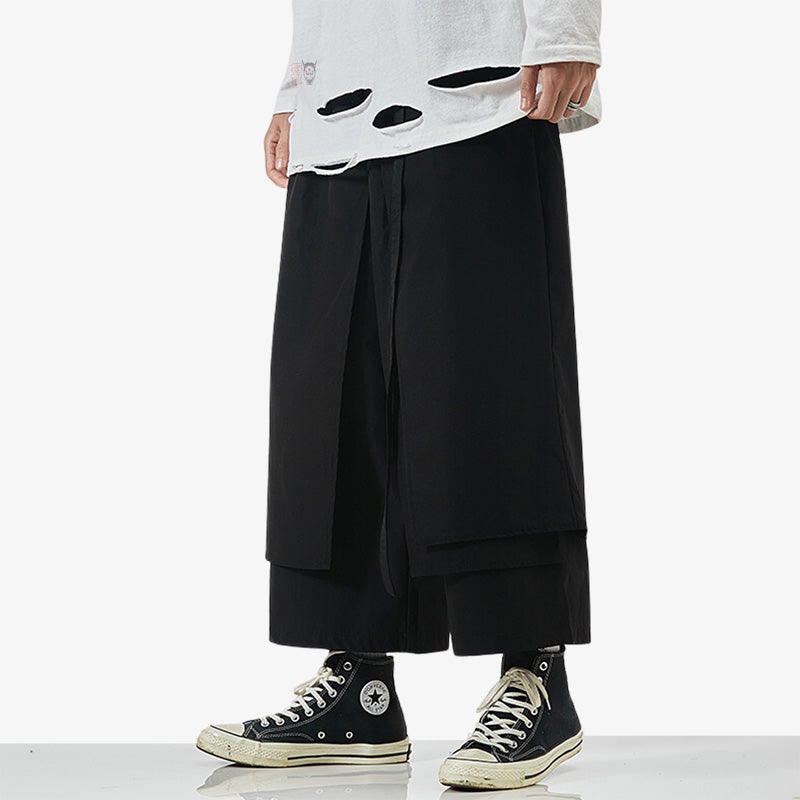 A man is dressed with black Japanese hakama pants and black sneakers.