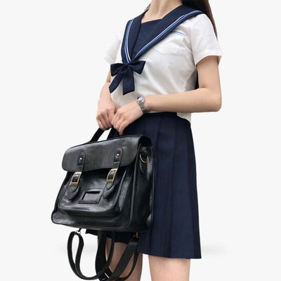 A woman carries a japanese high school bags. She is dressed in a Japanese sailor fuku uniform.