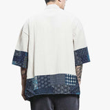 A man is wearing a Japanese kimono cardigan short. The haori jacket is white with the ends of the fabric decorated with geometric Japanese motifs.