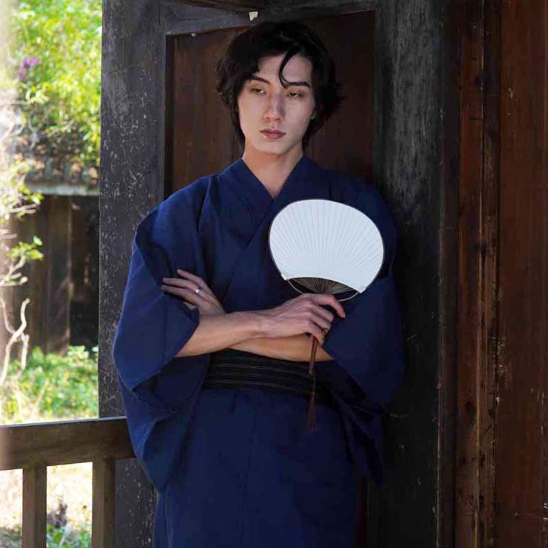 A man is wearing a traditional Japanese kimono robe men. He hold a white japanese sensu fan in his left hand.
