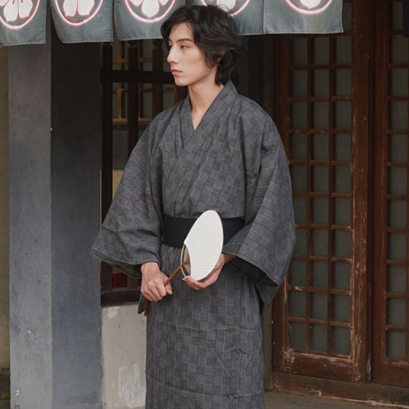 A man is dressed with Japanese Kimono Samura. The Japanese man holds a fan in his hand.