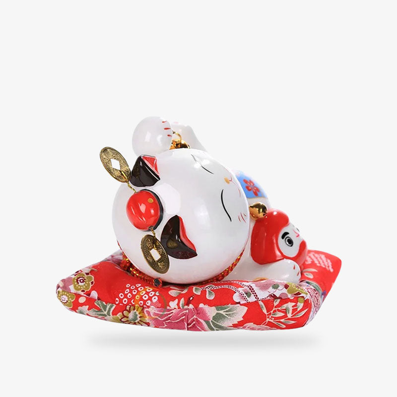 a Japanese maneki neko cat money made with ceramic cat lying on a red cushion
