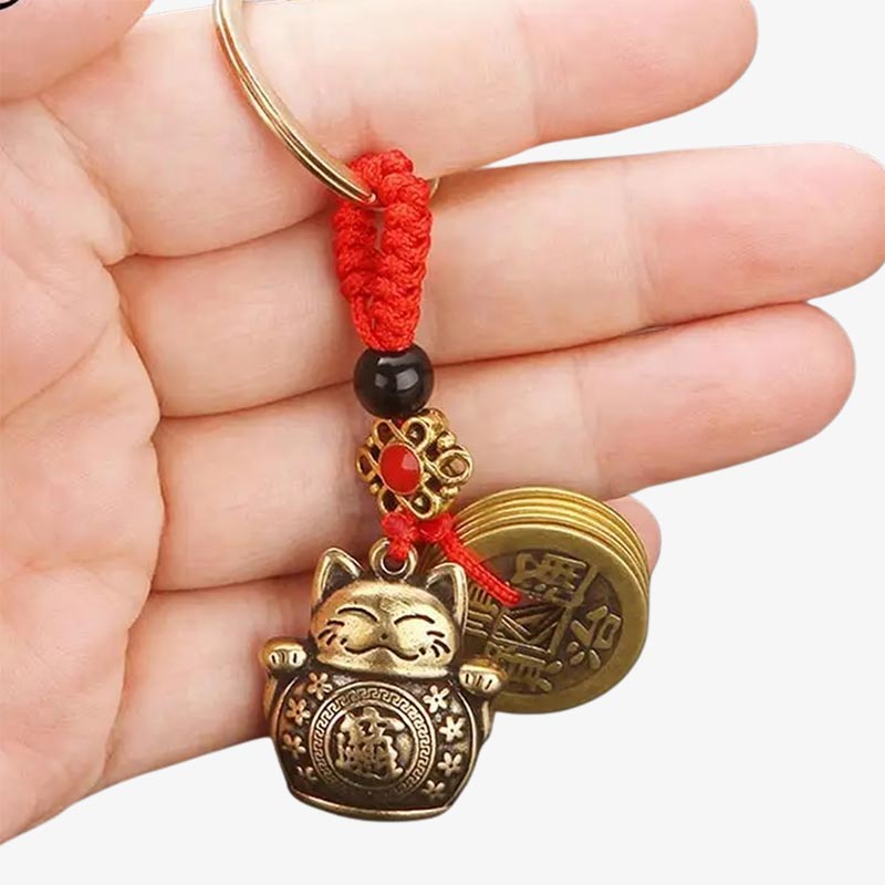 A person is holding in her hand a japanese maneki neko keychains charms with coins.