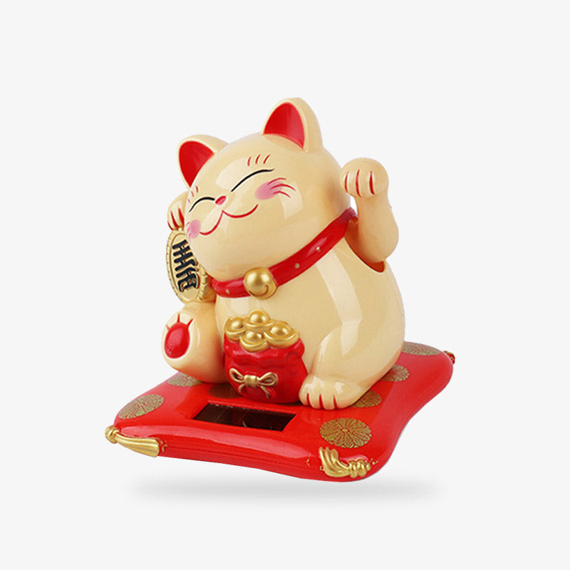 This japanese maneki neko lucky fortune cat is yellow and golden. This lucky Japanese cat is holding a golden koban in its right paw. His left paw is raised. There is a bag of gold coins in front of him. He has a red collar with a bell around his neck and the inside of his ears is also red.
