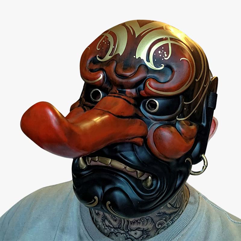 A man wear a japanese mask tengu. Mask material is wood and quality resin. The japanese mask has long noise. It's a traditional japanese mask symbolizing a oni demon. It's a popula manga mask