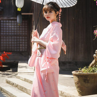A woman is wearing a traditional Japanese obi saura kimono and an Obi geisha belt around her waist. She holds a Japanese parasol in her hand. The geisha has a Kanzashi in her hair.