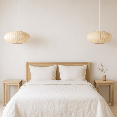 Bedroom with wooden headboard, white bedding, and japanese paper chandeliers​
pendant lights.