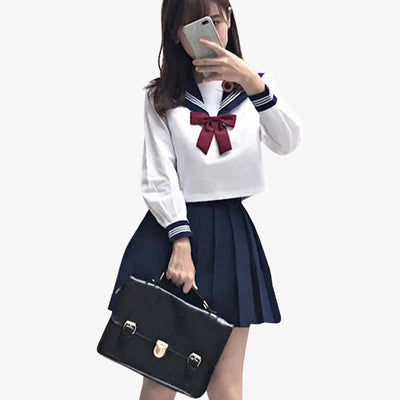 a girl is dressed with a japanese schoolgirl uniform cosplay. She holds a black japanese school bag. She wears a japanese skirt with blue color and white japanese student shirt