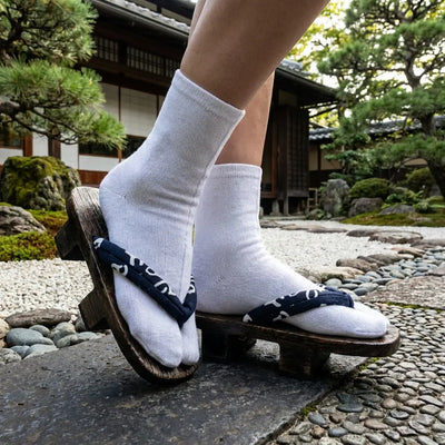 Japanese shoe with dark wood platform and navy lettered strap in garden setting