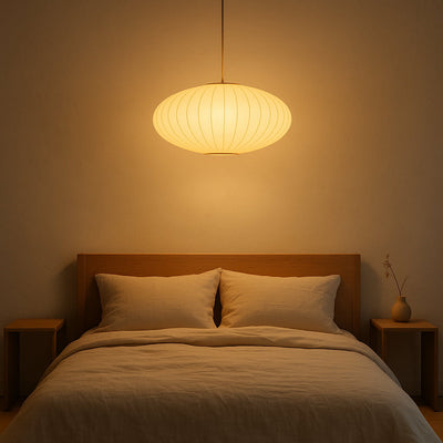 Bedroom with a wooden headboard, two pillows, and a hanging japanese silk chandelier lamp casting a warm glow.