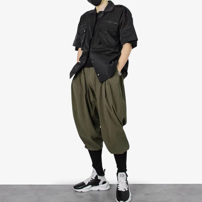 a man is dresses with Japanese streetwear loose pants and a black techwear shirt, and harajuku sneakers
