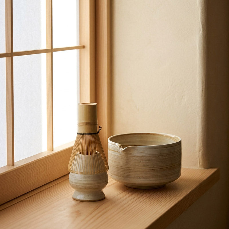Two ceramic items on a wooden surface near a window with soft natural light.