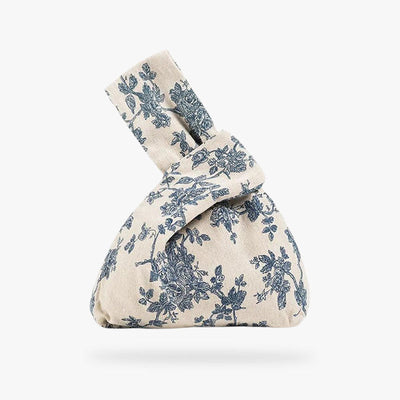 a traditional Japanese bag in white with a Japanese flower print. It's a fabric bow bag. Our Japanese Traditional Bag is inspired by the rich heritage of Japan, perfect for those who appreciate cultural authenticity in their accessories