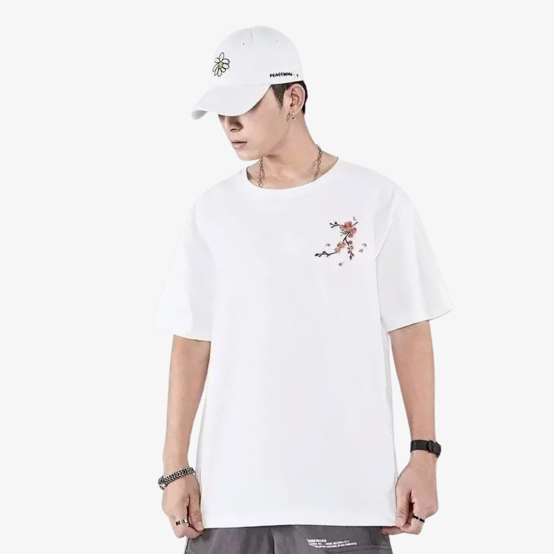Person wearing a Japanese white embroidered shirt with floral design and a white cap on a white background