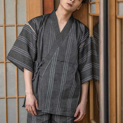 A man is dressed in Jinbei Japanese clothing men. This Japanese outfit is composed by a Traditional Kimono shirt, and a short pant made with linen and cotton material