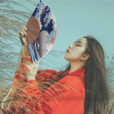 A woman carries a kanagawa fan in Japan. The folding fan is printed with The Great Japanese Wave by the artist Hokusai.