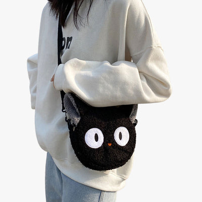 A woman is carrying a black kawaii cat bag on her shoulder. The Japanese shoulder bag is made of soft material. how off your love for felines with the Kawaii bag, a must-have for cat lovers and fans of cute accessories