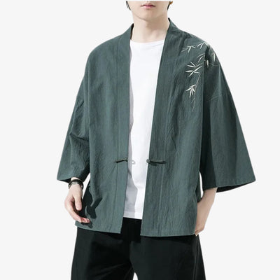 Person wearing a green kimono cardigan jacket embroidered style jacket with white embroidery on a white background