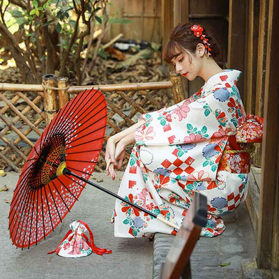 imono dress Japanese tradition style, adorned with sakura and fukiwa floral patterns on white fabric. A woman sit with a Japanese umbrella