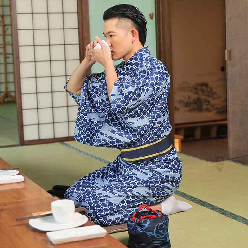 A Japanese man sits on a tatami mat and takes part in a tea ceremony. He is dressed with a kimono tea ceremony Kyoto. He is on a tatami in tradional japanse tea room