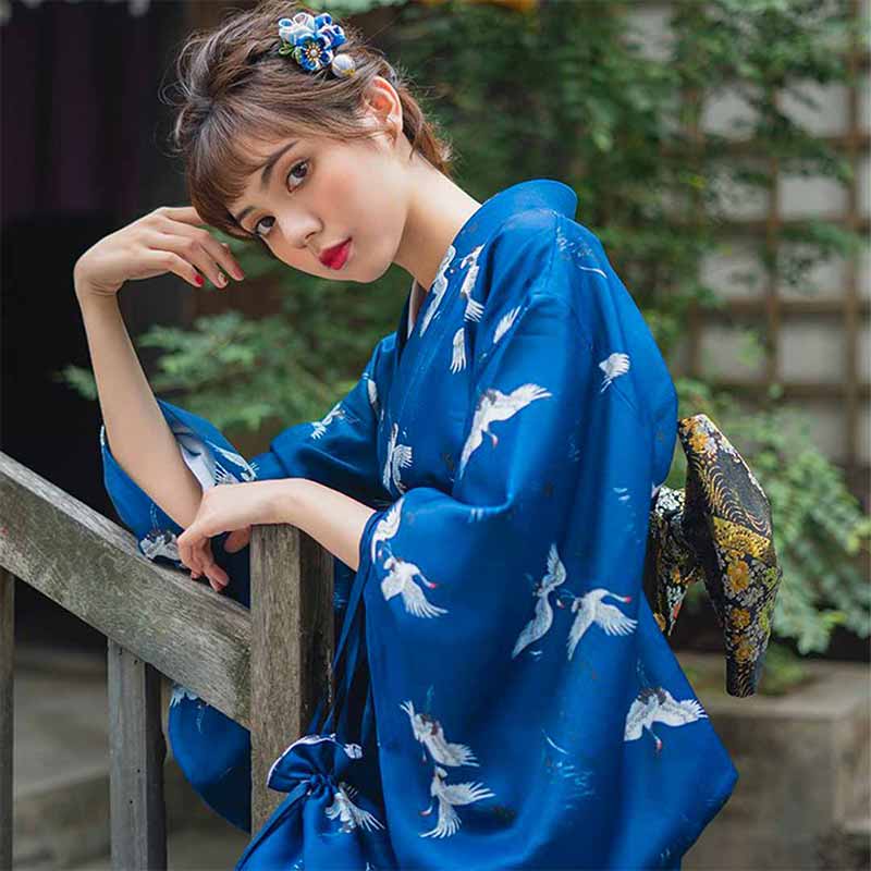 A woman is dressed with a kimono traditional printed with Japanese birds patterns