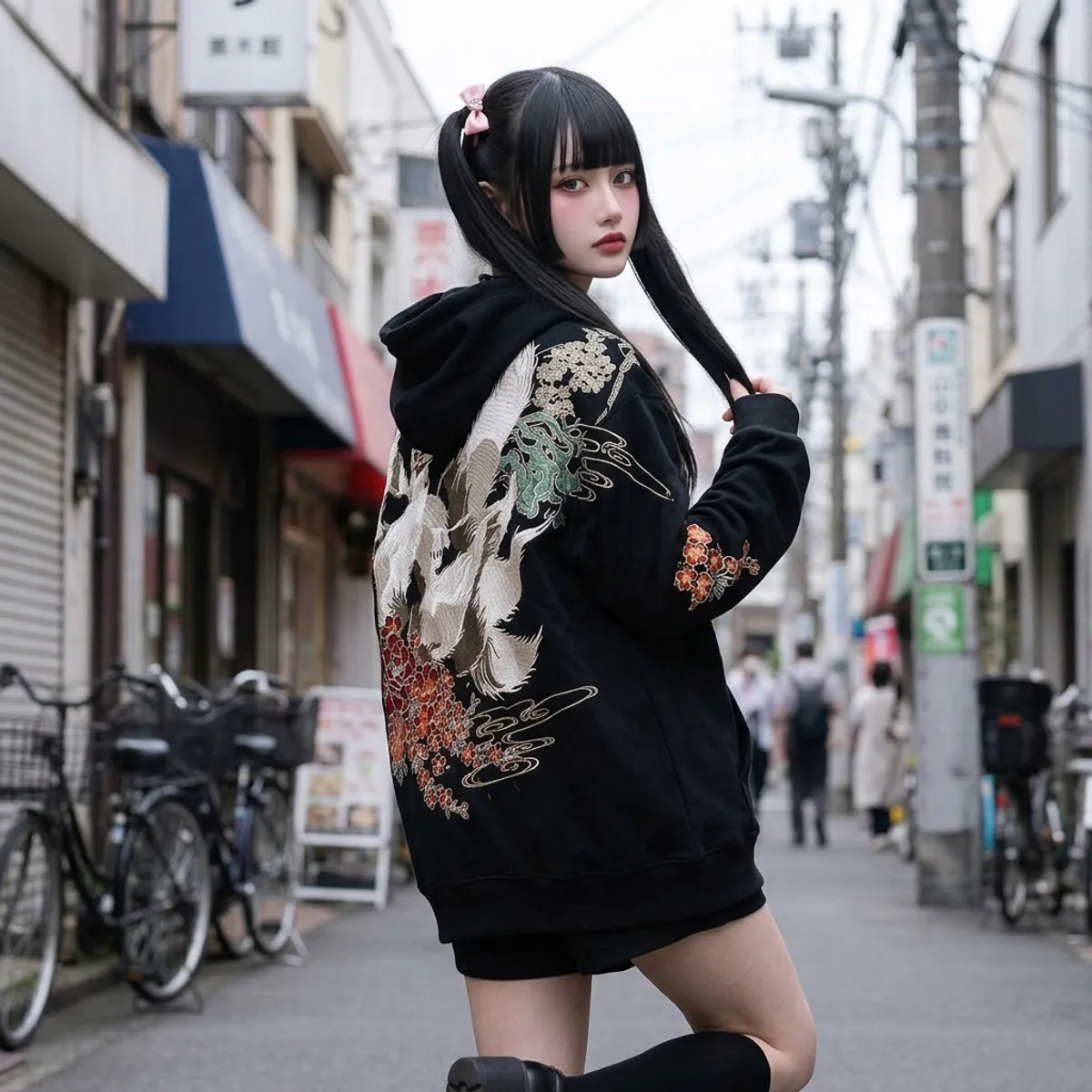 Kitsune hoodie worn oversized by a woman in Tokyo, looking over her shoulder at the white fox on the back