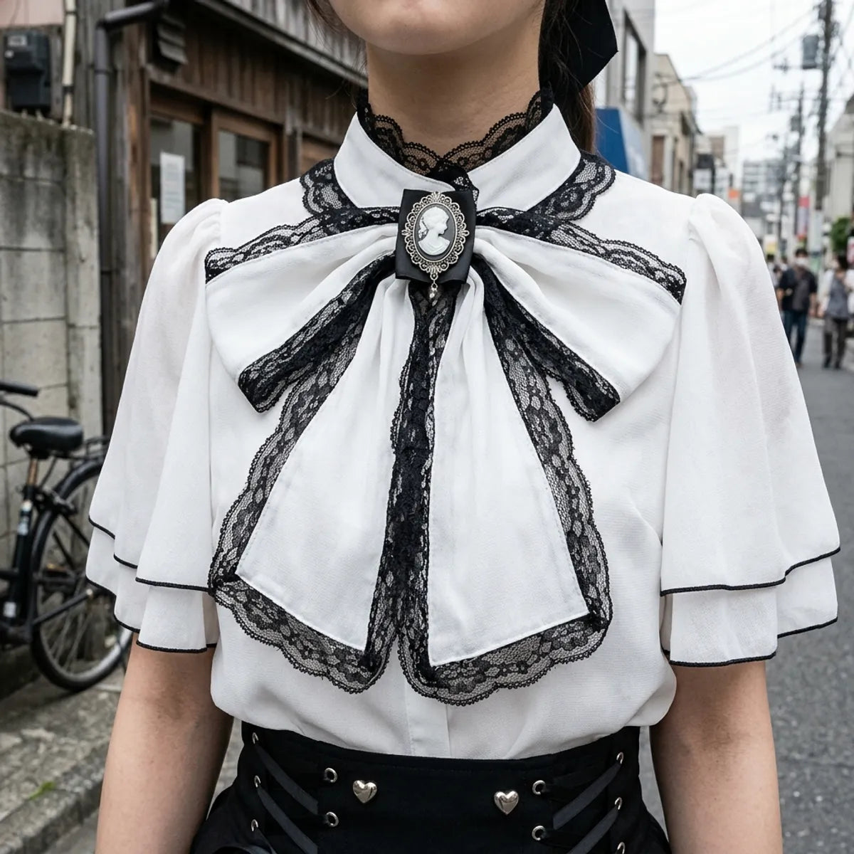 Close view of the black lace-edged bow, its silver cameo brooch and the capelet collar of the blouse