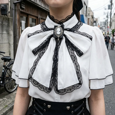 Close view of the black lace-edged bow, its silver cameo brooch and the capelet collar of the blouse