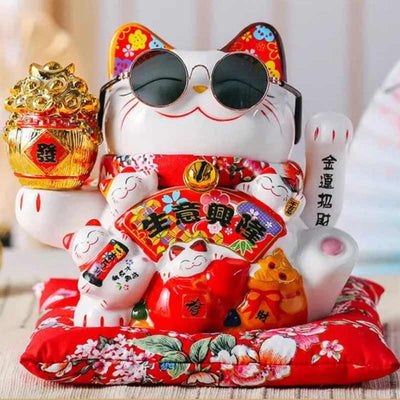 A large maneki neko lucky cat with a pair of glasses on its muzzle. The Japanese lucky cat has its left paw raised to attract good luck.
