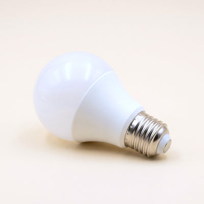 Frosted white LED bulb with an E27 screw base on a cream studio background
