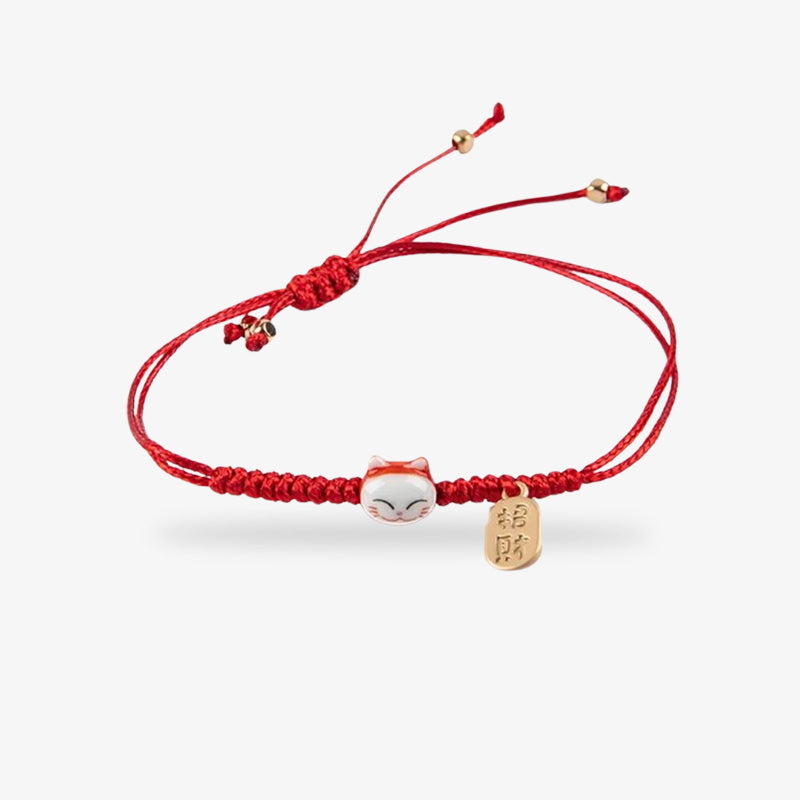 This maneki neko bracelet is red with a Japanese cat's head and a coin engraved with a gold-coloured kanji.