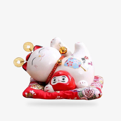 This Japanese maneki neko money cat is a ceramic maneki neko. It is a Japanese decorative object. It is also a money box for coins. He is holding a Daruma statuette in his paw.