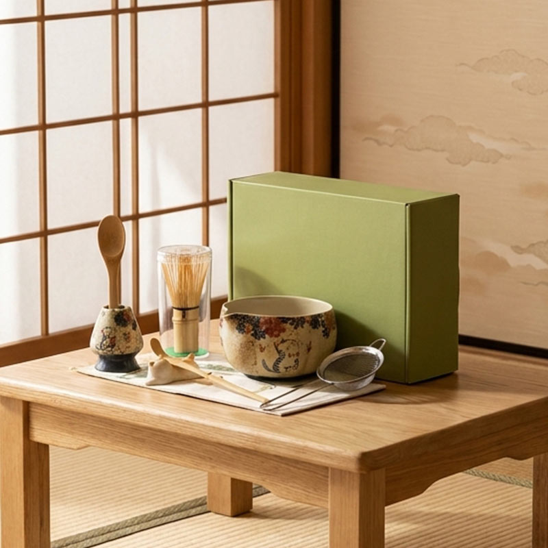 Green box on a wooden table with tmatcha set premium​ items in a traditional Japanese room.