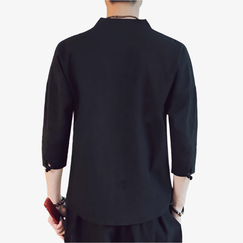 A man stands and is dressed with a black japan shirt