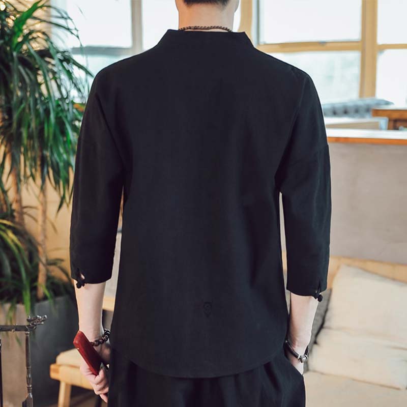 A man stands and is dressed with a black japan shirt