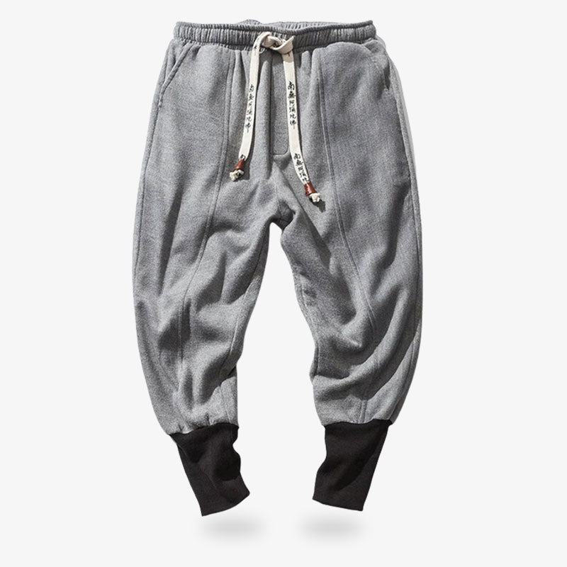 These modern ninja pants are grey and tightened at the ankles. These Japanese trousers are grey. The drawstring with Japanese kanji prints ties the garment together at the waist.