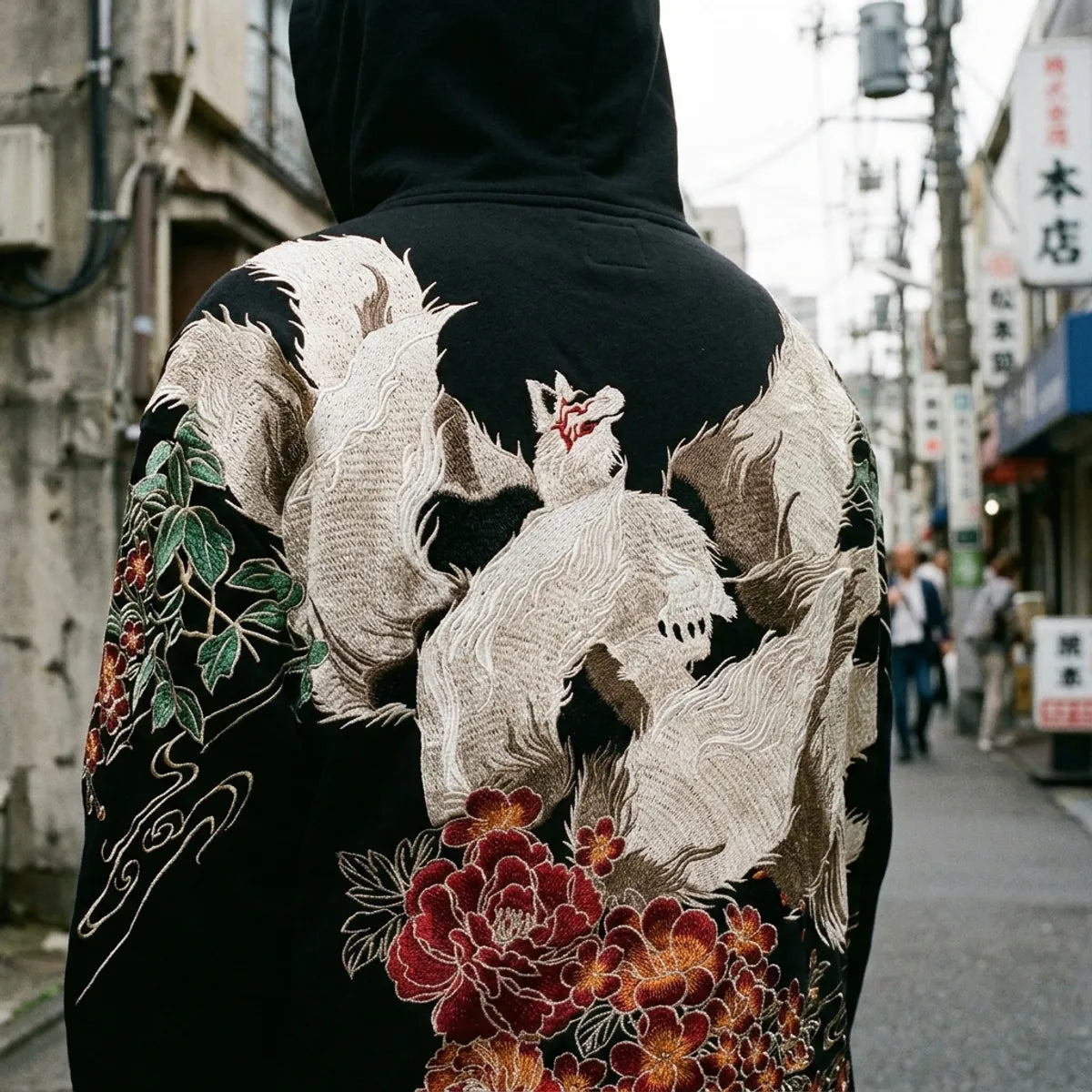 Close view of the nine-tailed fox embroidery on the back of the hoodie, white fur threads and a red mask