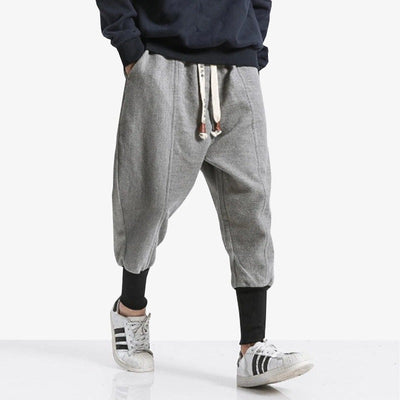 A man is dressed with mimalist grey ninja pants. The Japanese pants are tightened at the ankles.