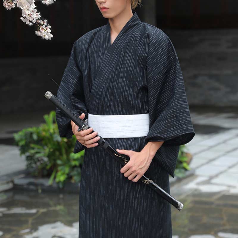 A man wearing a traditional kimono tied with a obi belt white. He holds a black katana in his hands