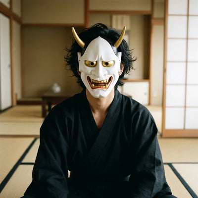 Front view of the glossy white Hannya demon mask with gold-painted horns and an open, fanged mouth.