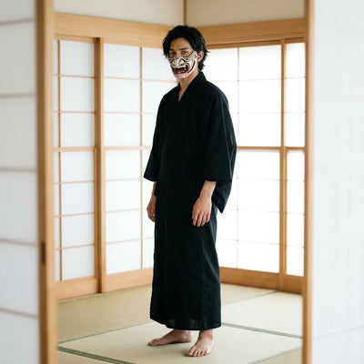 The oni demon mask displayed upright, showing its curved horn-like flares and snarling open mouth as it would hang on a wall.