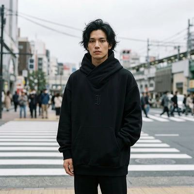 Oversized black sweatshirt with a wrap collar worn at a pedestrian crossing in Tokyo on a grey day
